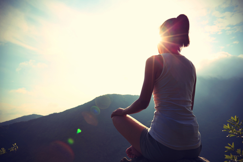 young yoga woman sit meditation on sunrise mountain peak rock